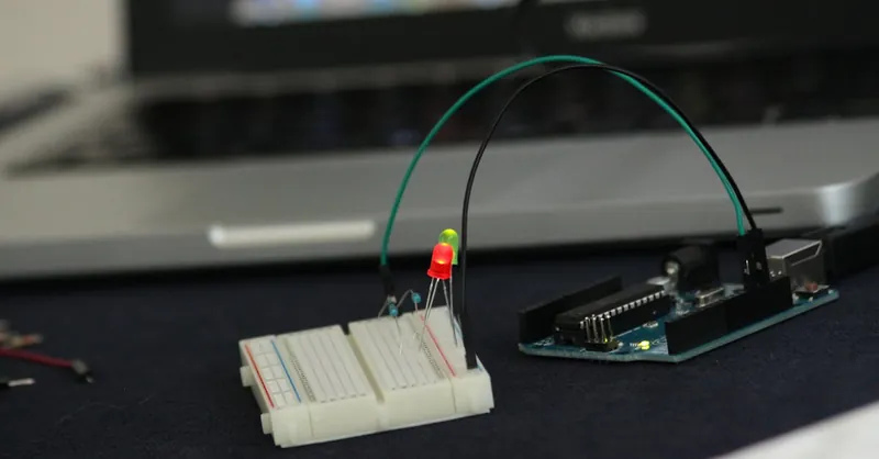 Close-up of an Arduino setup on a breadboard with glowing LED lights indoors.