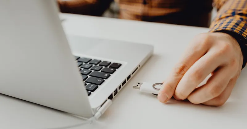 Close-up of a person inserting a USB drive into a laptop, symbolizing technology and data connection.