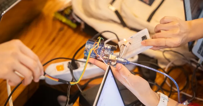 A detailed view of a team collaborating on an Arduino project featuring wiring and a breadboard.