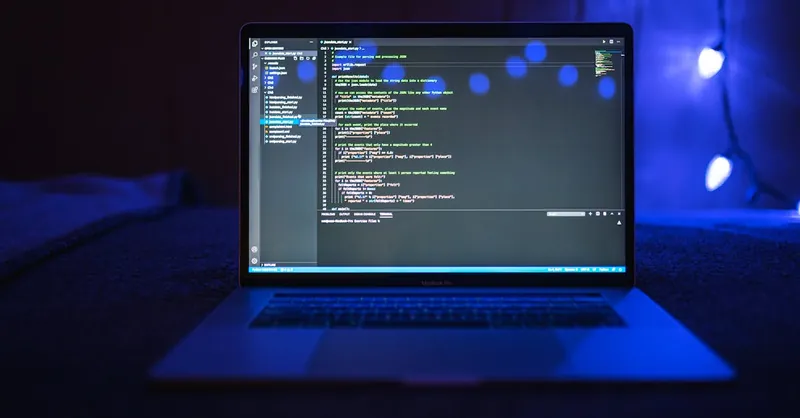Close-up of a laptop screen displaying code, set against a dark backdrop with blue lighting for a tech-focused ambiance.