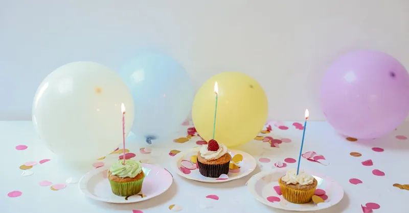 Festive setup with cupcakes, balloons, and confetti for a birthday celebration.