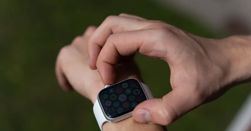 Detailed view of a hand interacting with a smartwatch outdoors.