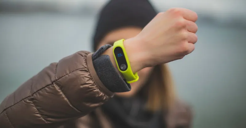 Close-up of a person holding up a fitness tracker, emphasizing technology and active lifestyle.