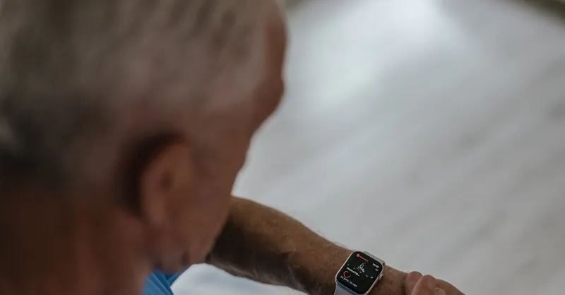 A senior man interacts with a smartwatch indoors, focusing on technology and lifestyle.